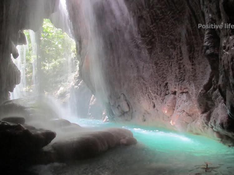 A grotto interior at Somerset Falls with mineral-aqua water and shafts of light