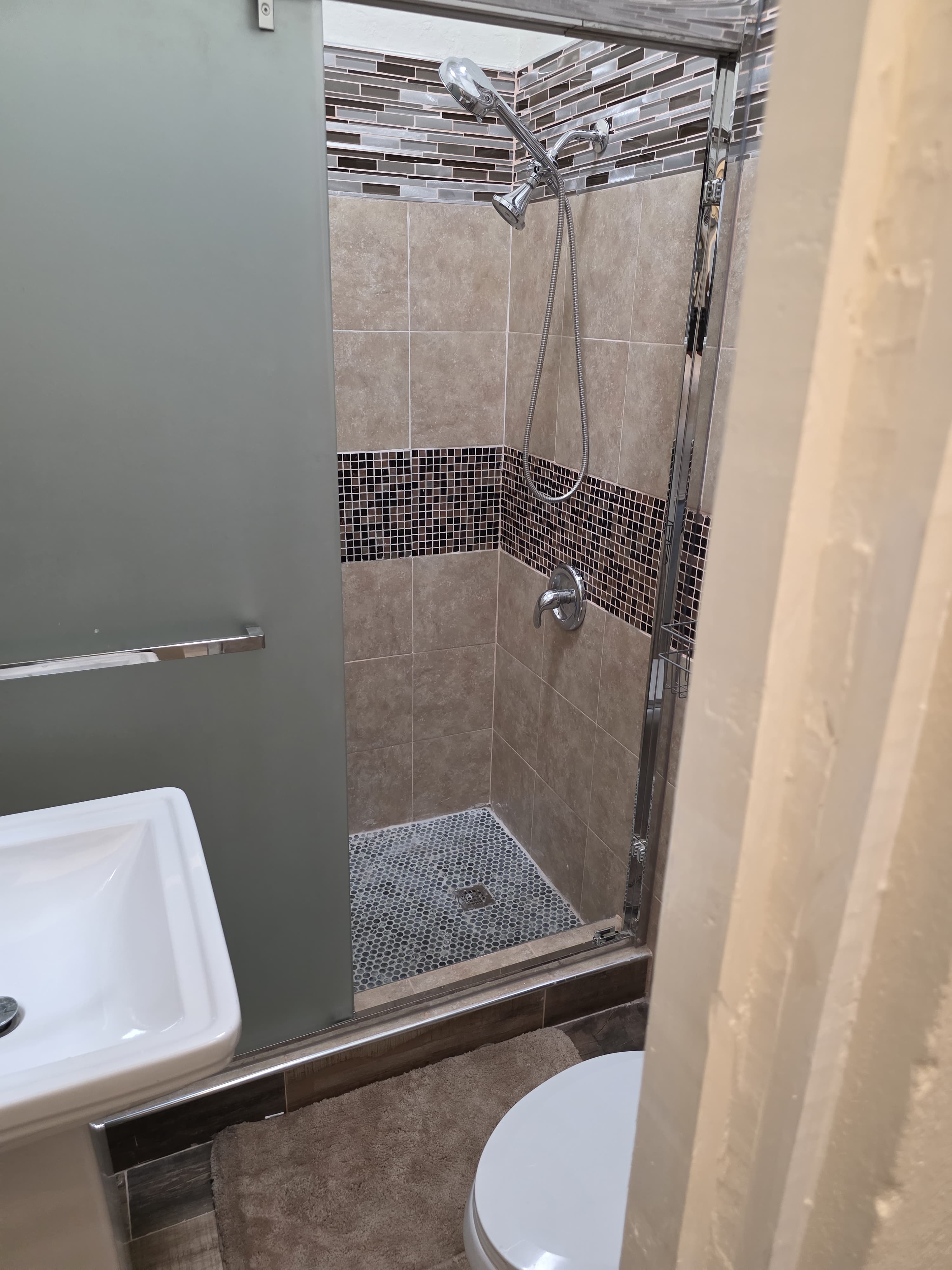 Tiled walk-in shower with mosaic detailing