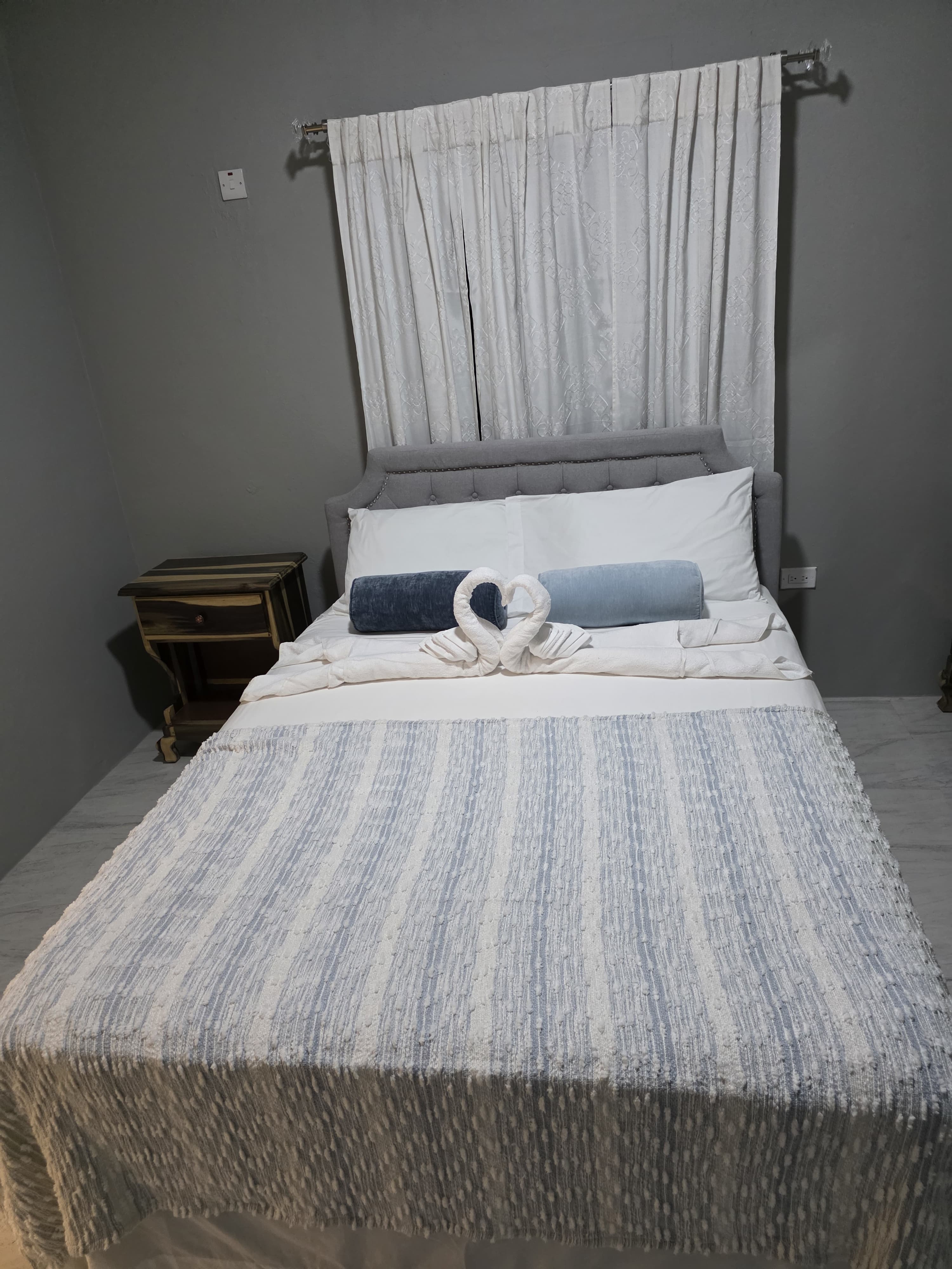 King bed with white linens and tall, gathered curtains
