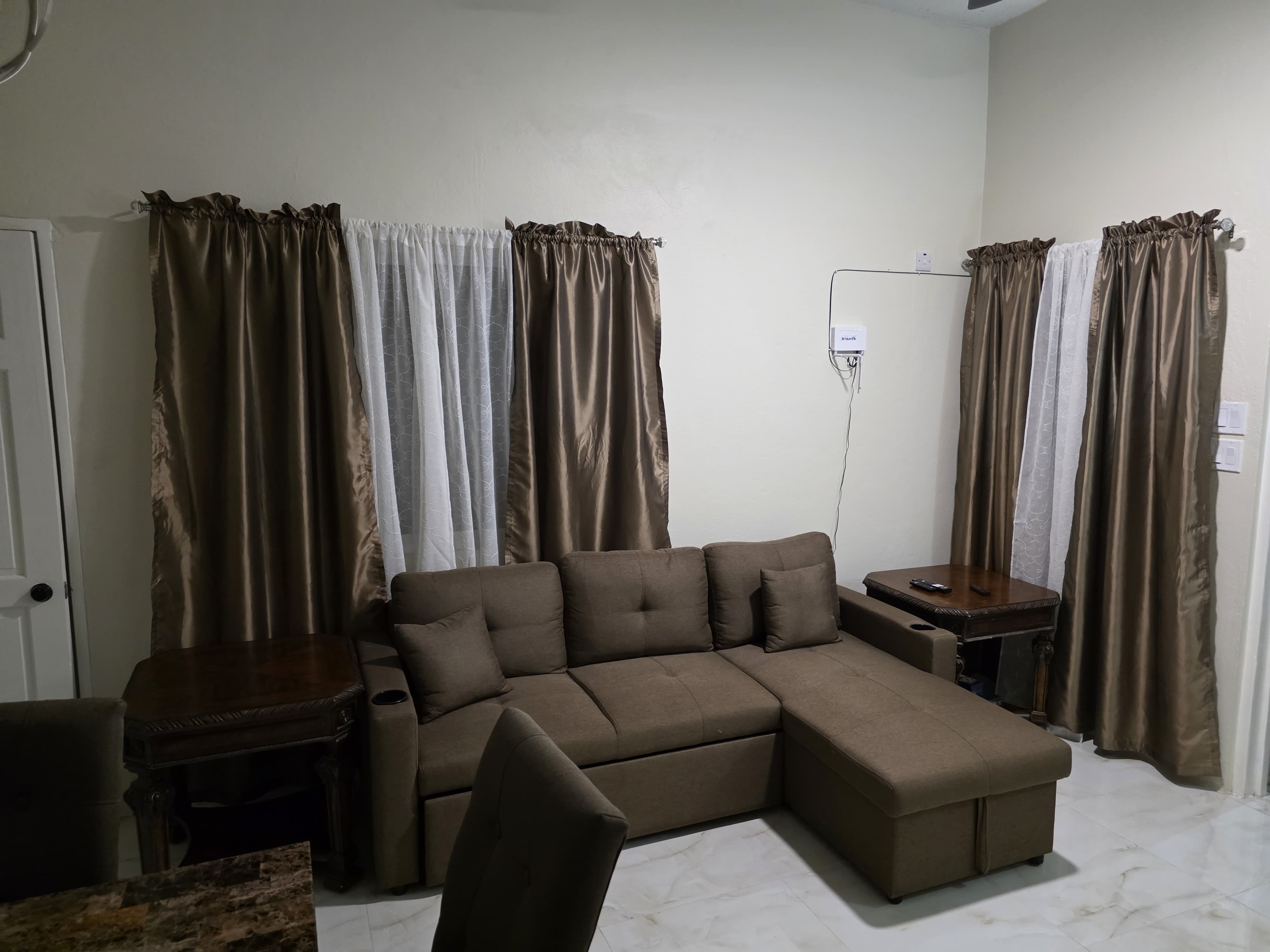 Sitting room with a brown sectional and tall curtains