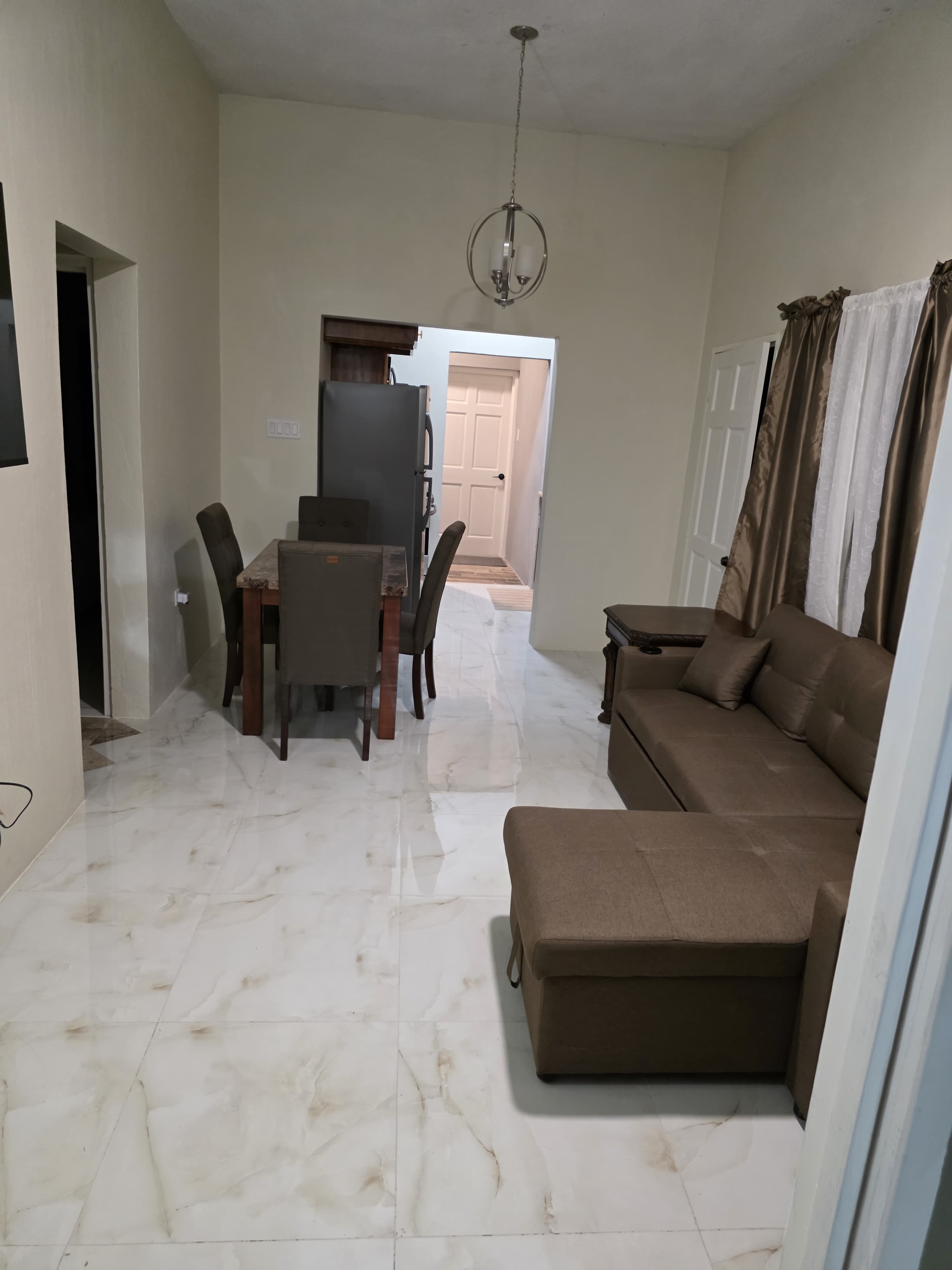 Open living and dining room with marble floors and pendant chandelier