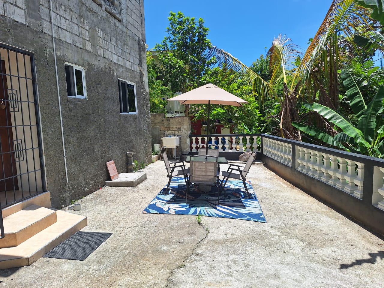 Private patio with an umbrella table under palm and banana trees