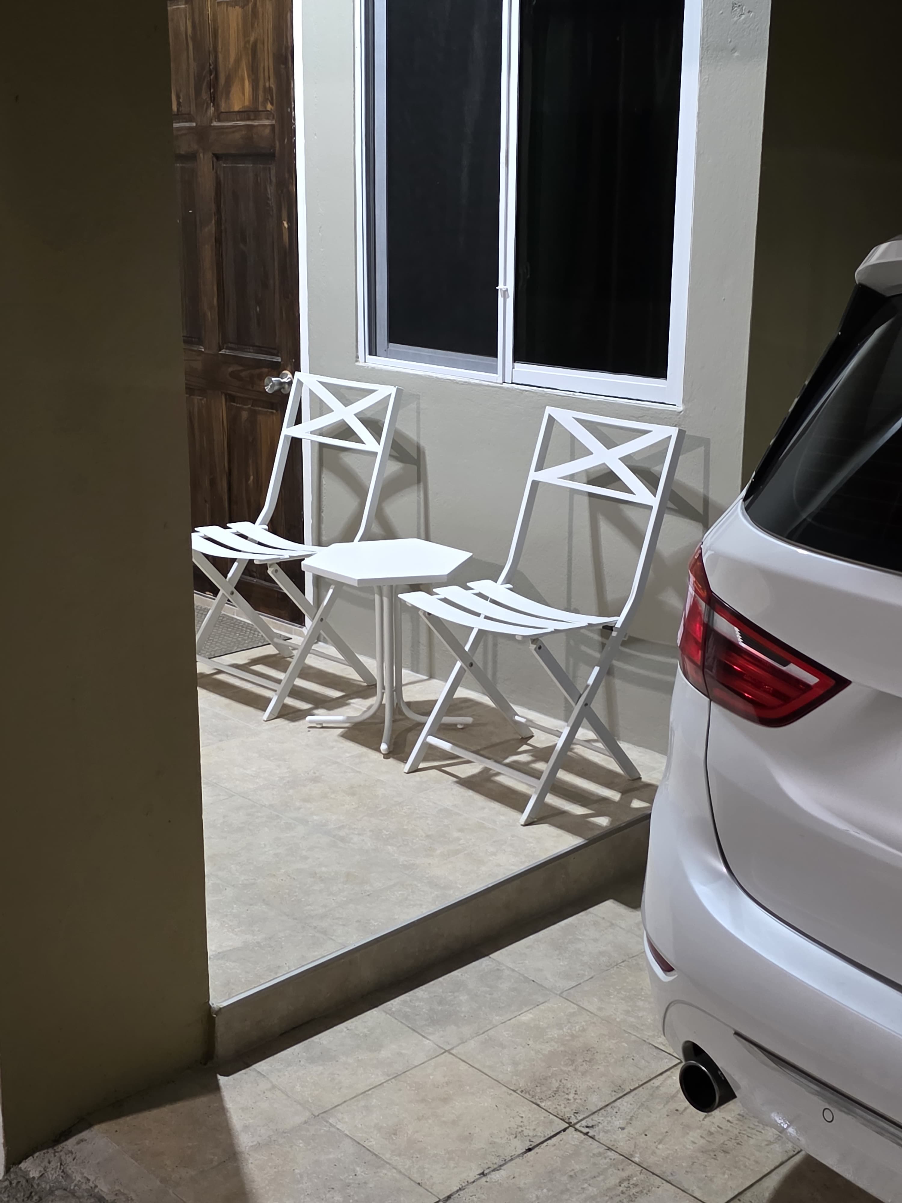 A pair of white bistro chairs and a small table on the estate patio