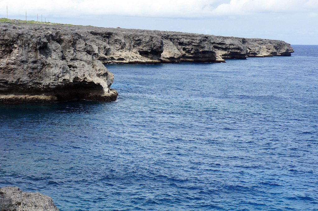 Caribbean coastal cliffs and deep blue water (placeholder image — to be replaced)